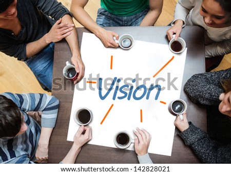 Team brainstorming over a poster on a table with vision written on it
