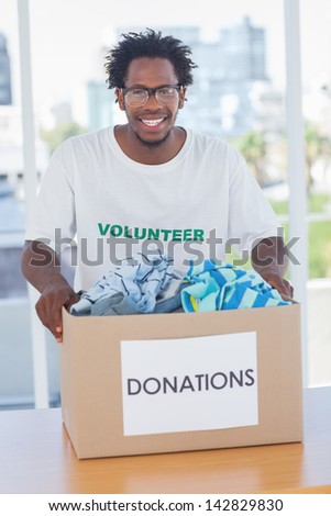 Happy man holding donation box with clothes
