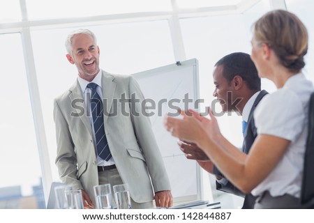 Colleagues applauding smiling manager during a meeting in a meeting room