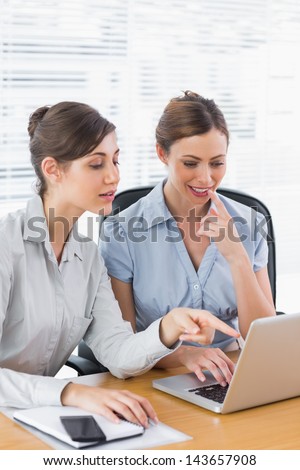 Happy businesswomen working together on a laptop at desk in office