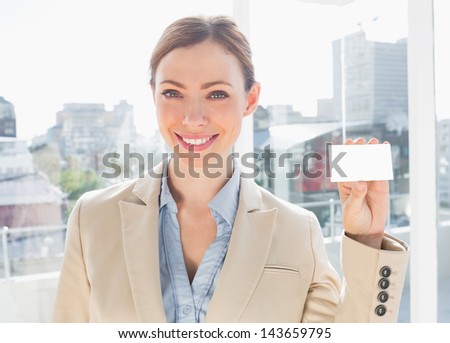 Smiling businesswoman showing blank business card in bright office