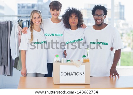 Volunteers standing in front of food in a donation box in their office