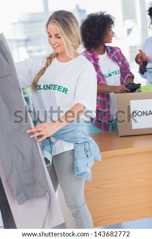 Smiling volunteers putting clothes in clothes rail in their office