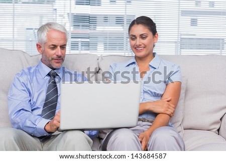 Business people looking at laptop and smiling in staffroom