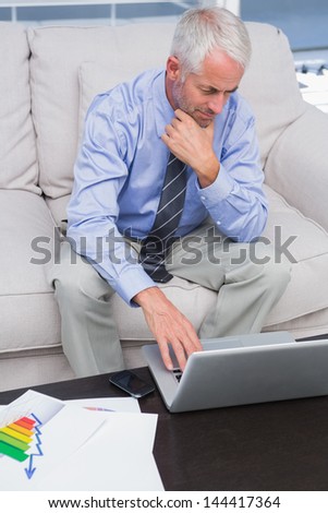 Businessman doing work with his laptop sitting on couch in office