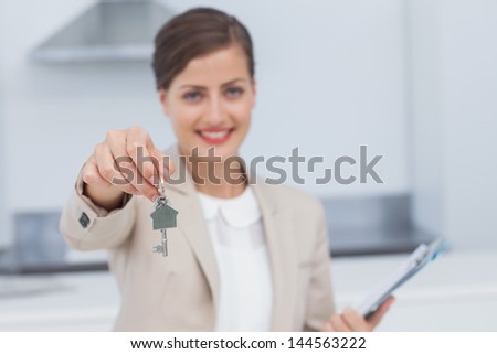 Pretty real estate agent giving house key in a kitchen