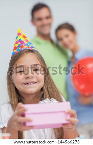 Little girl holding a birthday present during her birthday