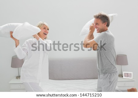 Couple having a pillow fight at home in bedroom