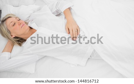 Blonde woman in a deep sleep at home in her bed