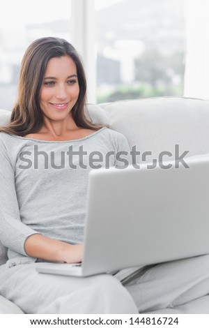 Woman relaxing and using her laptop sat on a couch