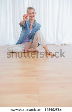 Happy blonde woman showing new house keys and smiling at camera