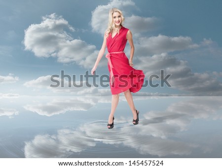 Fashion woman wearing a red dress and walking on a puddle