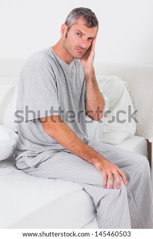 Worried man holding his head and sitting in bed