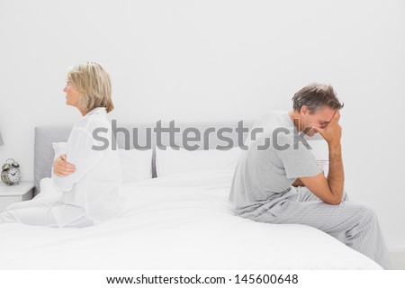 Couple sitting on opposite sides of bed after a dispute