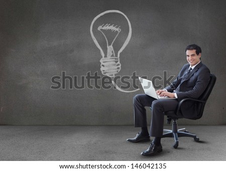 Businessman using his laptop with arrow graphic coming from it in empty grey room