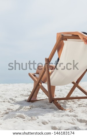 Woman resting on her deck chair in front of ocean on beach