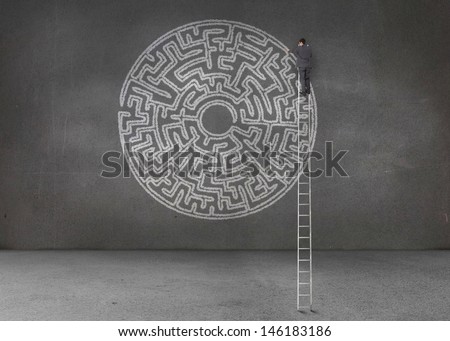 Businessman drawing a labyrinth in an empty dark room