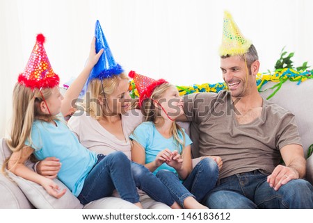 Family celebrating twins birthday sitting on a couch in the living room