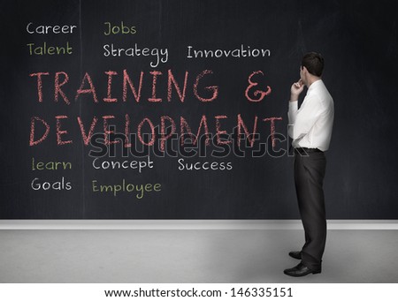 Businessman looking at training and development terms written on a blackboard