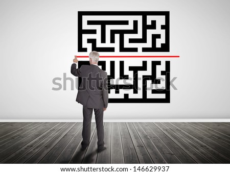 Businessman drawing red line through quick response code on a wall