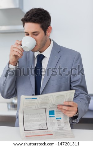 Businessman drinking a coffee and reading a newspaper before going to work