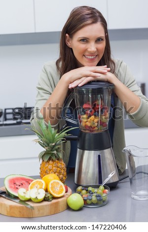 Woman leaning on her blender in the kitchen