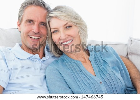 Happy couple on their couch smiling at camera