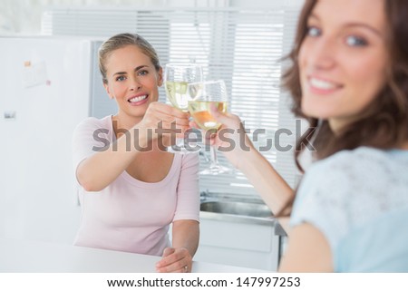 Happy women in the kitchen holding glasses of white wine