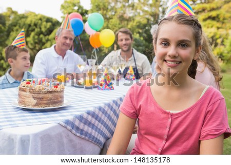Little girl smiling at camera at her birthday party outside at picnic table