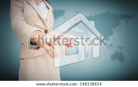 Businesswoman touching house graphic on world map background