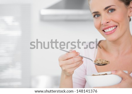 Happy woman holding bowl of cereal in her kitchen
