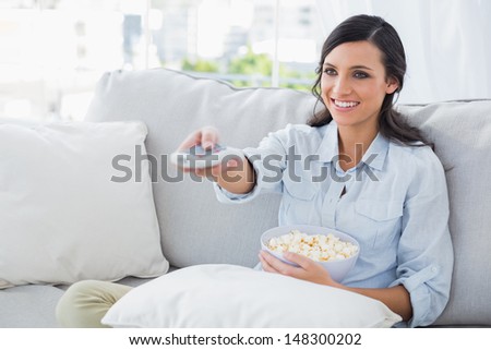 Pretty woman watching tv eating popcorn in her living room