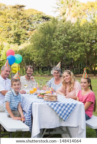 Happy family smiling at camera at birthday party outside at picnic table