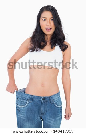 Sexy woman wearing too big jeans on white background