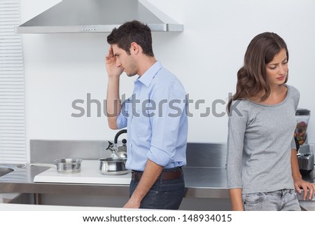 Couple sulking at each other in the kitchen after a dispute