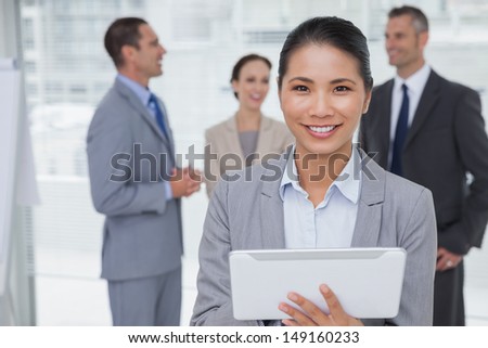 Businesswoman in bright office using her tablet pc while colleagues talking together