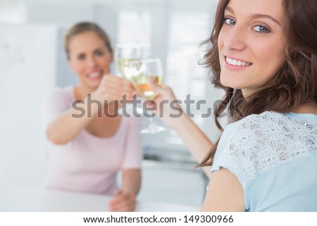 Cheerful women in the kitchen holding glasses of white wine