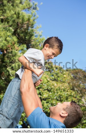 Father lifting up his son on a beautiful day in the park