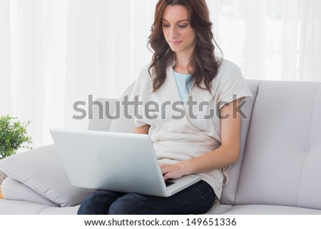 Relaxed woman with laptop on her knees and sitting on the couch
