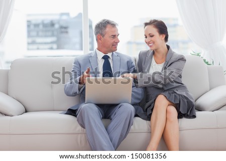 Cheerful workmates working together sitting on sofa in cosy bright office