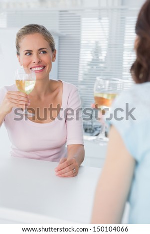Radiant women having glass of wine in the kitchen