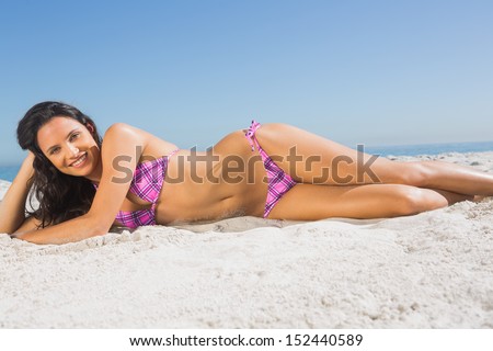 Smiling attractive tanned woman sunbathing on the beach