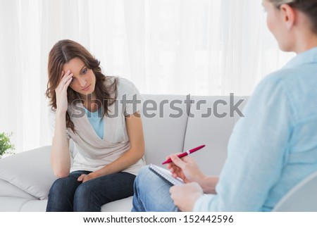 Worried woman sitting while therapist looking at her in a private session