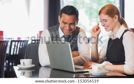 Happy business team working together in a cafe with laptop