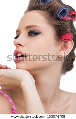 Thoughtful model with hair curlers on white background