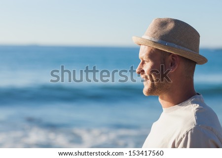 Handsome man wearing straw hat looking at the sea on the beach