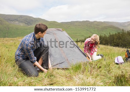 Happy couple pitching their tent in the countryside