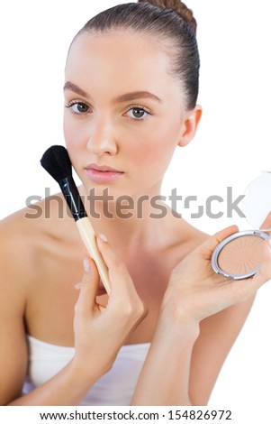 Sensual model with powder compact and powder brush looking at camera