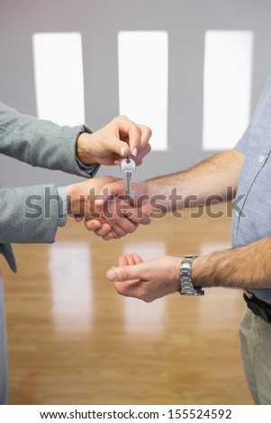 Close up of a man receiving a handshake and a key at the same time in a room