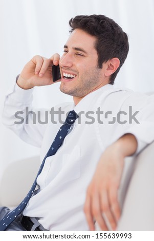 Happy businessman calling with his mobile phone on sofa at office